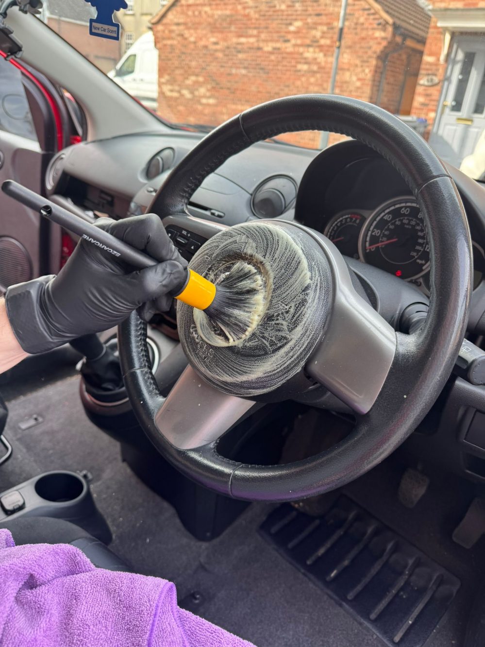 Steering wheel being cleaned with brush